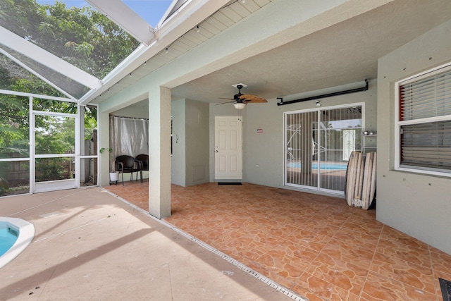 view of patio featuring ceiling fan and glass enclosure