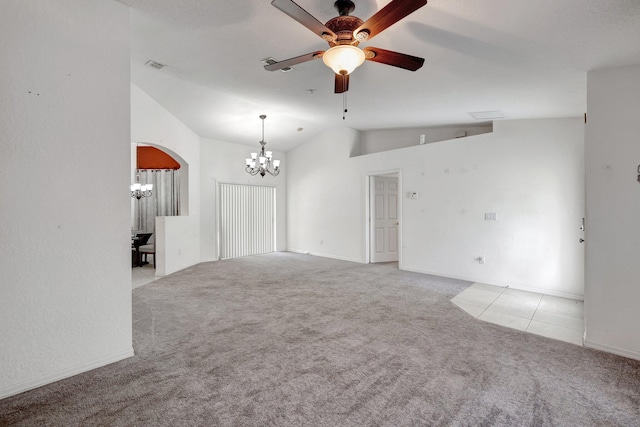 carpeted empty room with high vaulted ceiling and ceiling fan with notable chandelier