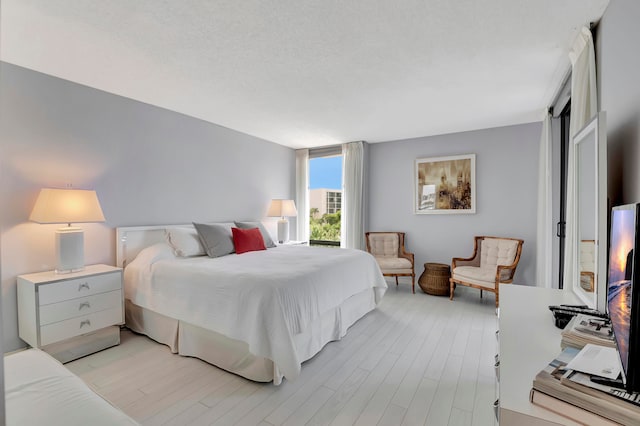 bedroom with a textured ceiling and light wood-type flooring