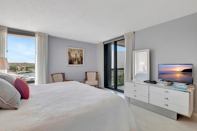 bedroom featuring a textured ceiling, light wood-type flooring, and access to outside