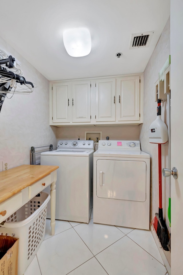 clothes washing area with hookup for a washing machine, washer and dryer, light tile flooring, and cabinets