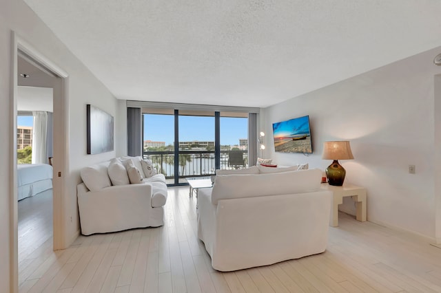 living room with light hardwood / wood-style flooring, a textured ceiling, and a wall of windows