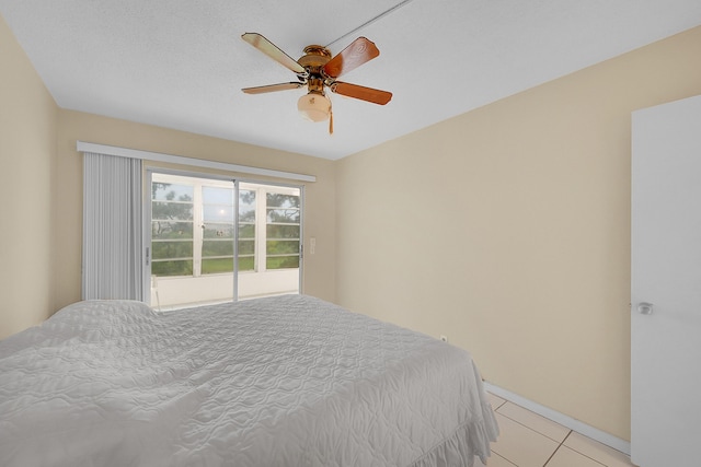 bedroom featuring ceiling fan, light tile patterned floors, and a textured ceiling