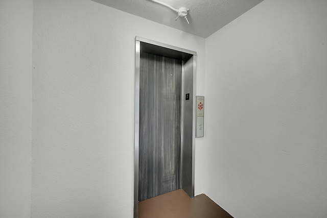 interior space featuring a textured ceiling and elevator