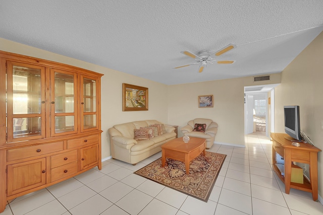 living room with ceiling fan, light tile patterned floors, and a textured ceiling