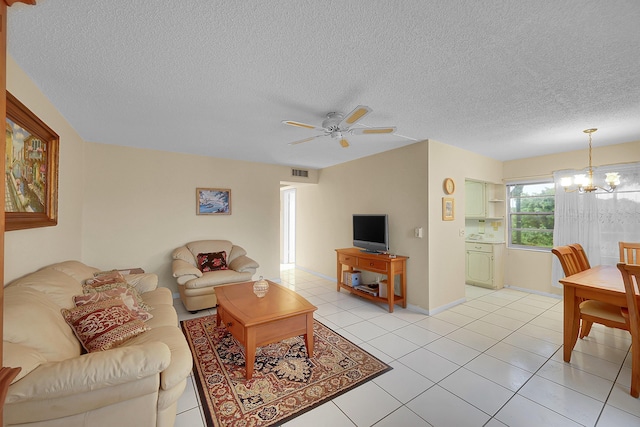 tiled living room featuring a textured ceiling and ceiling fan with notable chandelier