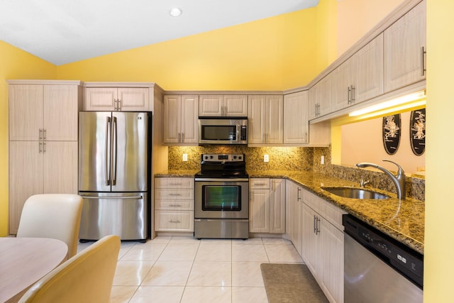 kitchen featuring vaulted ceiling, stainless steel appliances, tasteful backsplash, sink, and light tile floors