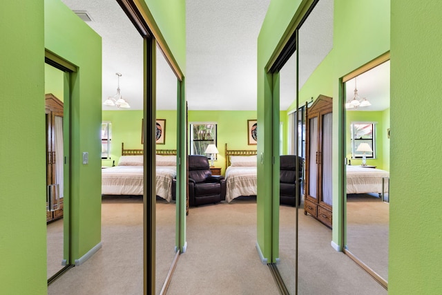 hallway with carpet flooring, a towering ceiling, a chandelier, and a textured ceiling