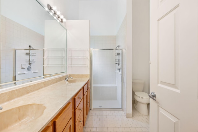 bathroom featuring a shower with door, double sink vanity, tile flooring, and toilet