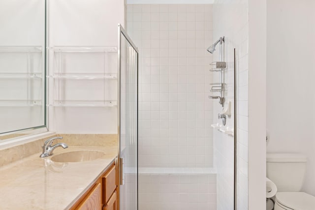 bathroom with vanity with extensive cabinet space, toilet, and a shower with door