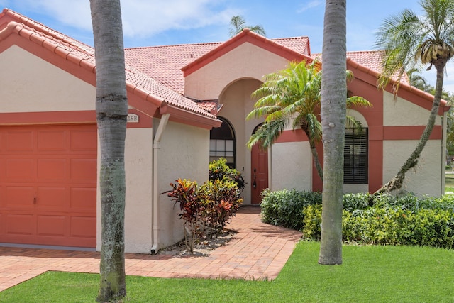 mediterranean / spanish home featuring a front yard and a garage