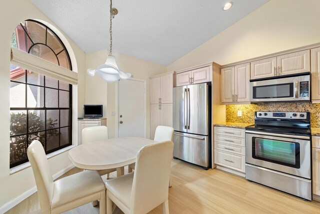 7825 Lexington Club Blvd Unit B, Delray Beach, FL 33446 - kitchen featuring light wood-style flooring, appliances with stainless steel finishes, decorative backsplash, and vaulted ceiling