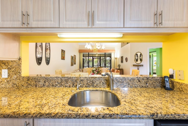 kitchen with sink, light stone countertops, a chandelier, and tasteful backsplash