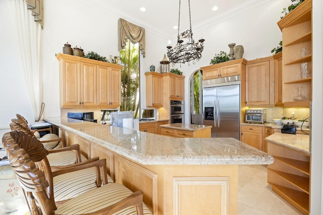 kitchen featuring a center island, stainless steel appliances, a notable chandelier, kitchen peninsula, and a breakfast bar