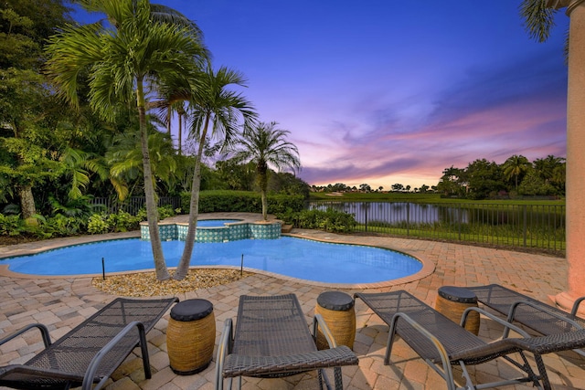 pool at dusk with a water view, an in ground hot tub, and a patio