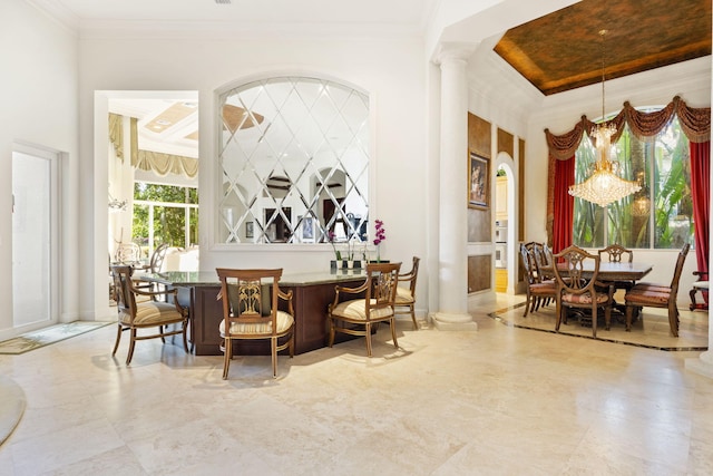 dining room featuring a notable chandelier, crown molding, and decorative columns