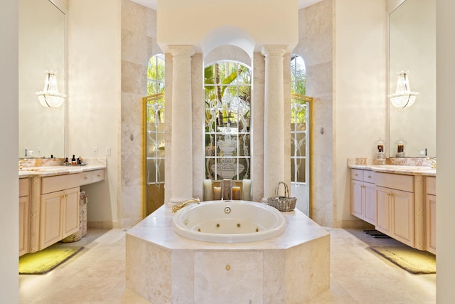 bathroom featuring vanity, decorative columns, and tiled tub