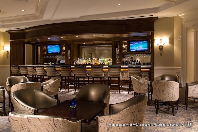 bar featuring a raised ceiling and ornamental molding