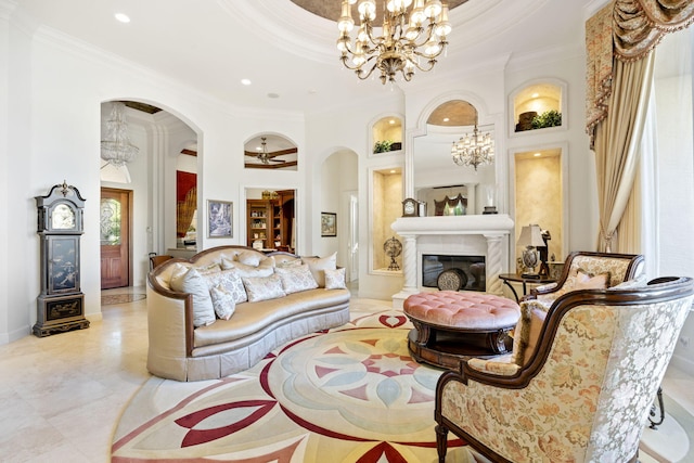 living room with a towering ceiling, ceiling fan with notable chandelier, and ornamental molding