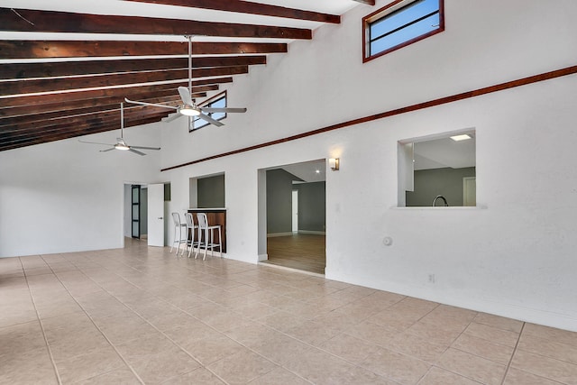 empty room featuring beam ceiling, high vaulted ceiling, ceiling fan, and light tile floors