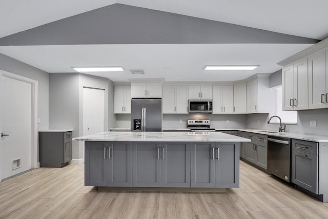 kitchen featuring light wood-type flooring, gray cabinets, appliances with stainless steel finishes, a large island, and a sink