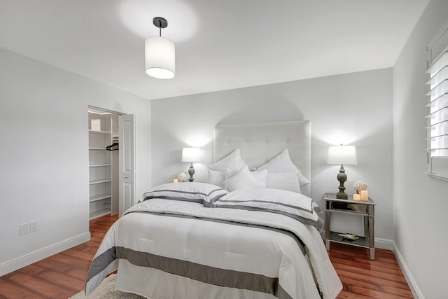 bedroom with dark hardwood / wood-style flooring, a walk in closet, and a closet