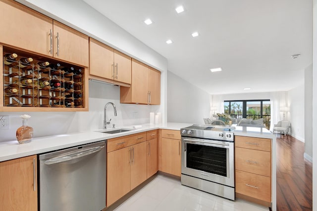 kitchen featuring sink, kitchen peninsula, stainless steel appliances, and light brown cabinetry