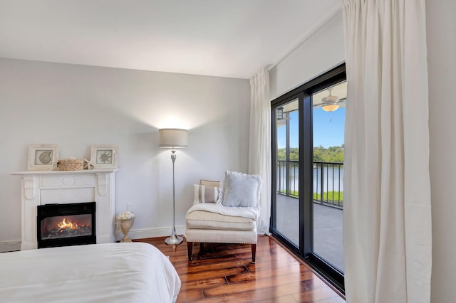 bedroom featuring hardwood / wood-style floors, access to outside, and a water view