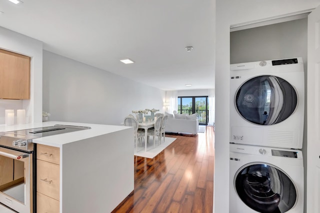 laundry room featuring dark wood-type flooring and stacked washer / drying machine