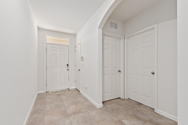 hall with a textured ceiling and light tile patterned flooring