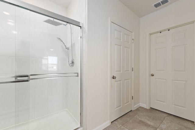 bathroom with a shower with door and tile patterned floors