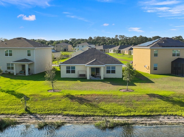 rear view of house with a water view and a lawn