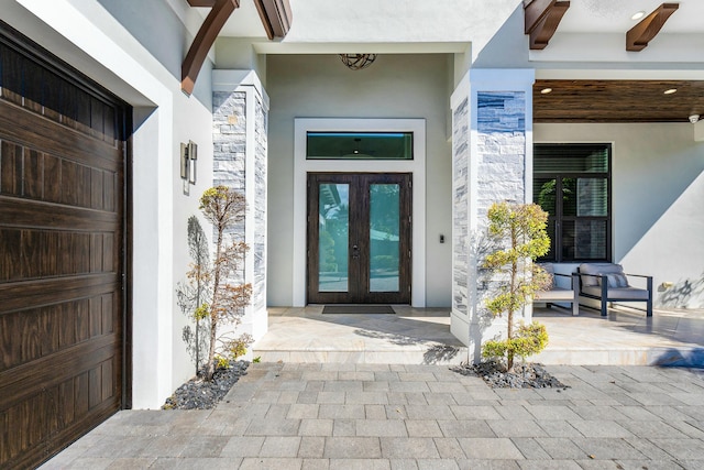 hall featuring a barn door, a raised ceiling, light wood-type flooring, and french doors