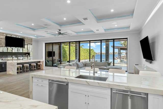 bedroom featuring a water view, light hardwood / wood-style flooring, ceiling fan, access to exterior, and a tray ceiling