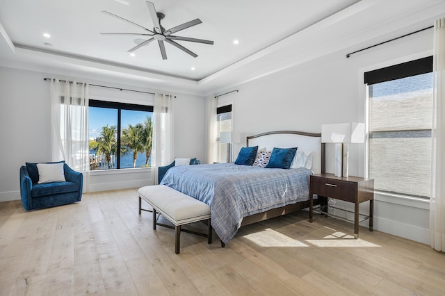 bedroom featuring wood-type flooring, a water view, and multiple windows