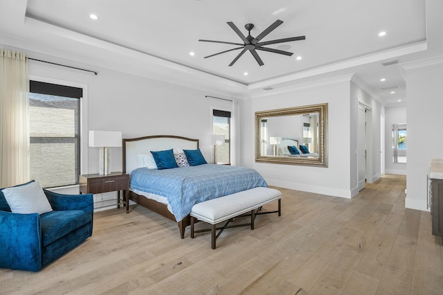 bedroom with stainless steel refrigerator, ceiling fan, light hardwood / wood-style floors, a tray ceiling, and a water view