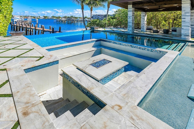 view of pool with a water view, an in ground hot tub, and a patio