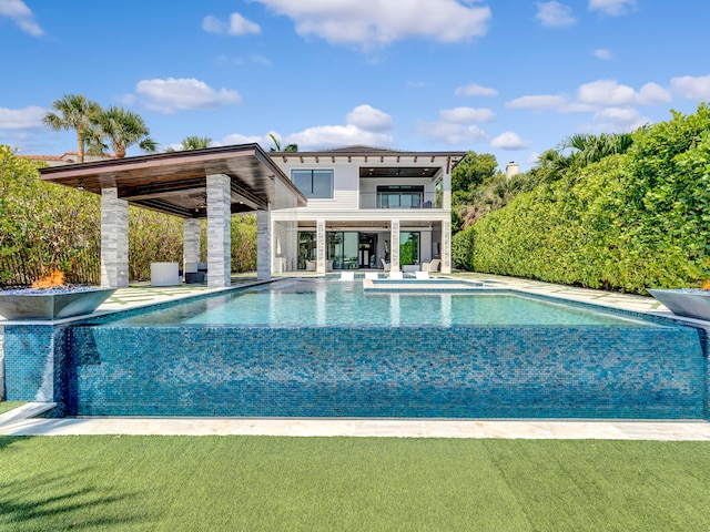 rear view of property featuring ceiling fan, a swimming pool with hot tub, a balcony, and a patio area