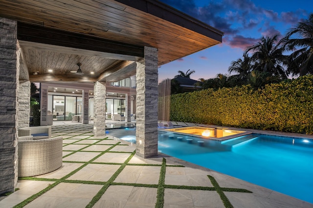 back house at dusk with ceiling fan, a balcony, an outdoor fire pit, and a patio