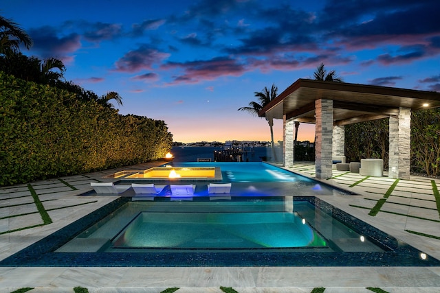 pool at dusk featuring a jacuzzi, a patio, and ceiling fan