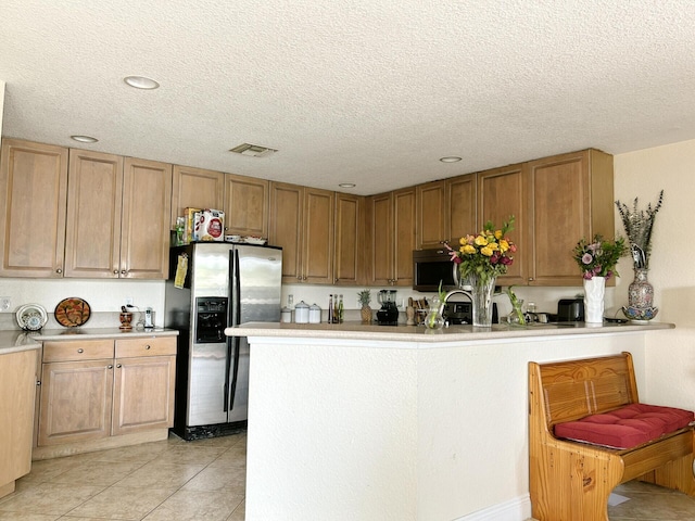 kitchen with stainless steel appliances, a textured ceiling, and light tile floors