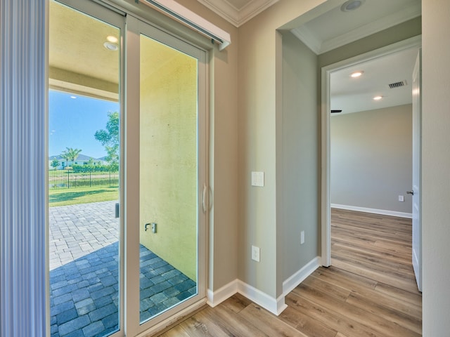 doorway with light hardwood / wood-style floors and crown molding