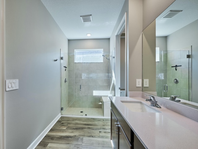 bathroom featuring walk in shower, vanity, a textured ceiling, and hardwood / wood-style flooring