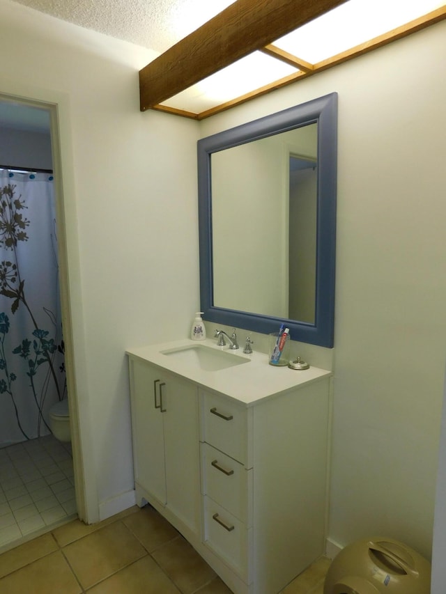 bathroom with tile flooring, a textured ceiling, toilet, and large vanity