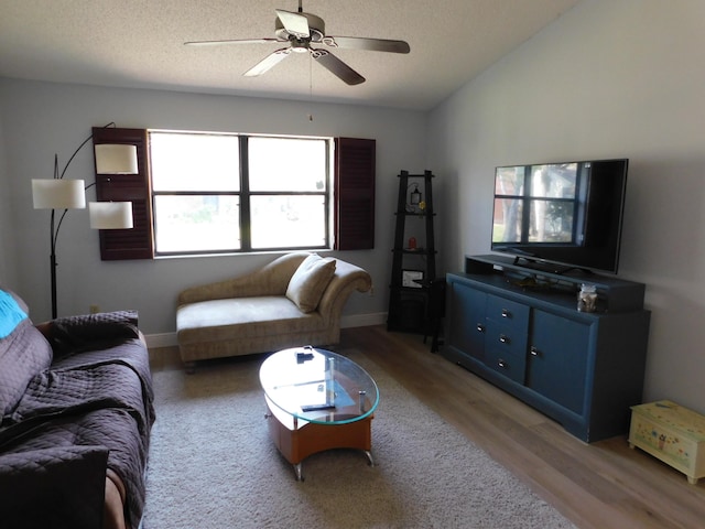 living room with hardwood / wood-style flooring, lofted ceiling, ceiling fan, and a textured ceiling