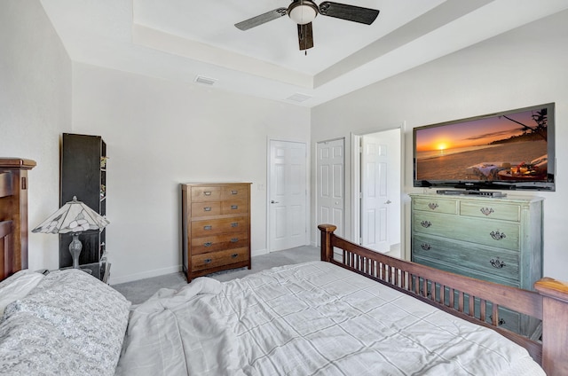 carpeted bedroom featuring a raised ceiling and ceiling fan