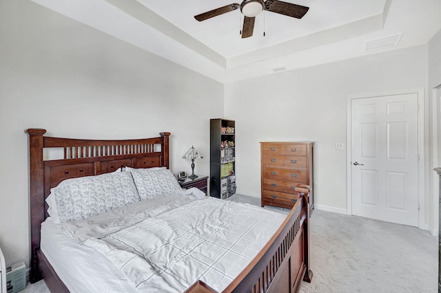 bedroom with ceiling fan, a raised ceiling, and light colored carpet