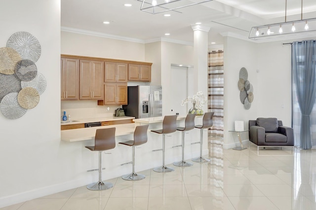 kitchen featuring ornate columns, stainless steel fridge, a breakfast bar, light tile patterned flooring, and ornamental molding