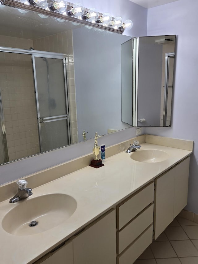 bathroom with a shower with shower door, vanity, and tile patterned flooring