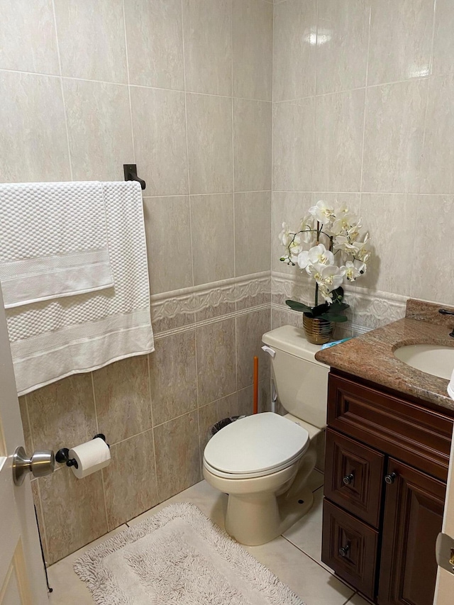 bathroom featuring tile patterned floors, vanity, tile walls, and toilet